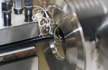 Fine turnings fly off a fast spinning metal lathe © Jake Hellbach